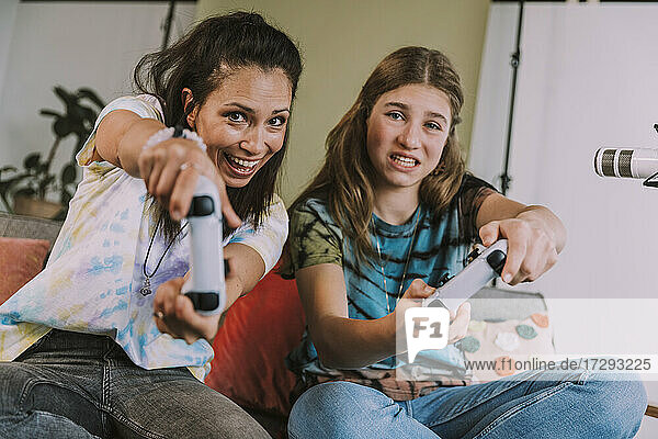 Happy female gamers playing video game while vlogging at home