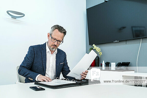 Businessman checking paperwork while working in office