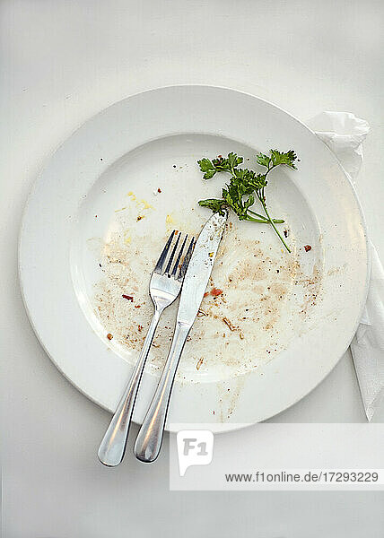 Plate with leftovers and cutlery on table