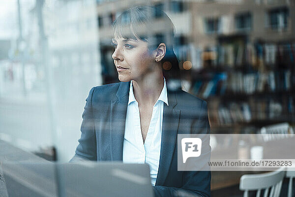Nachdenkliche Geschäftsfrau schaut durch das Fenster eines Cafés