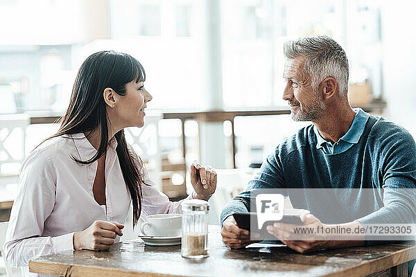 Lächelnde Geschäftsfrau  die mit einem Kollegen in einem Café diskutiert