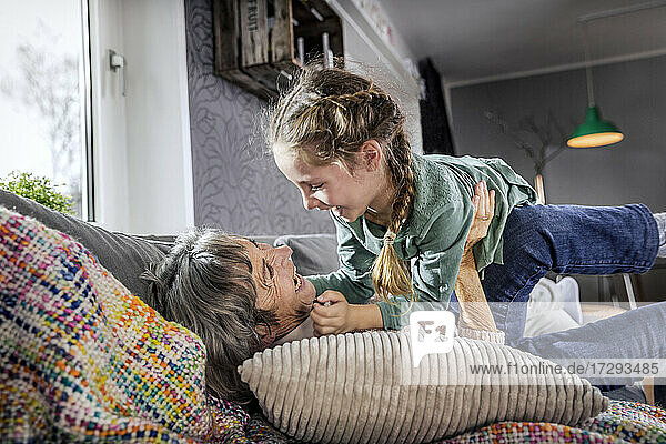 Großmutter spielt mit Enkelin auf dem Sofa liegend zu Hause