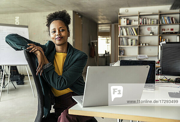 Geschäftsfrau sitzt auf einem Stuhl vor einem Laptop am Schreibtisch