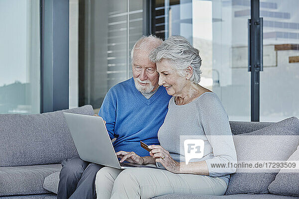 Älterer Mann und Frau benutzen Laptop beim Online-Shopping zu Hause
