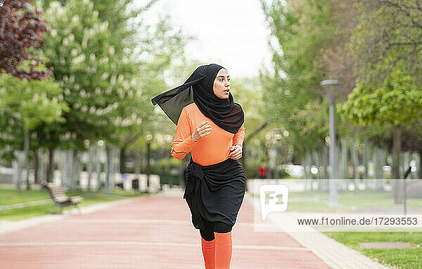Schöne Frau mit Kopftuch schaut beim Laufen im öffentlichen Park weg