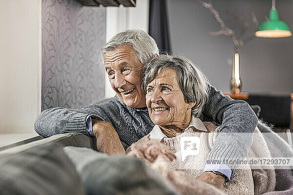 Thoughtful senior couple looking away at home