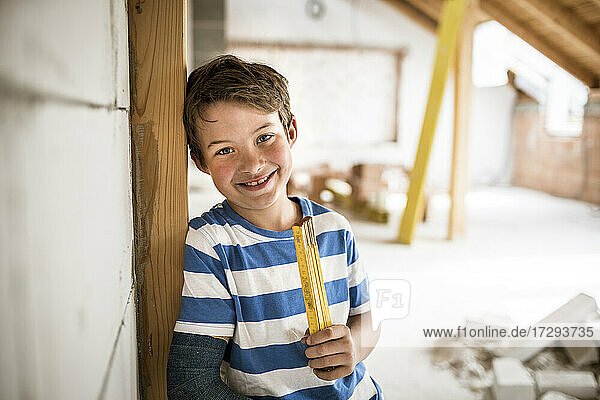 Smiling boy holding tape measure during house renovation