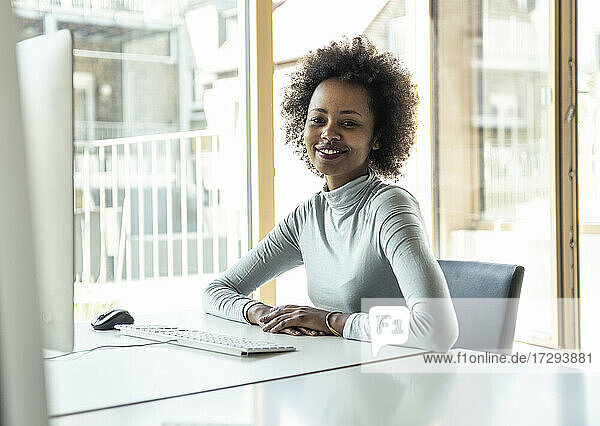Lächelnde weibliche Fachkraft sitzt am Schreibtisch