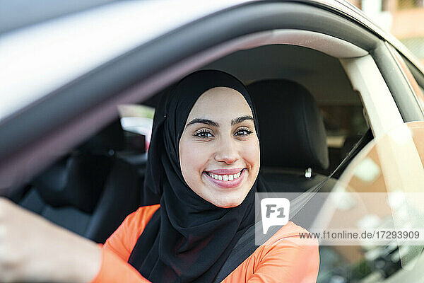 Arabische Frau mit Kopftuch sitzt im Auto