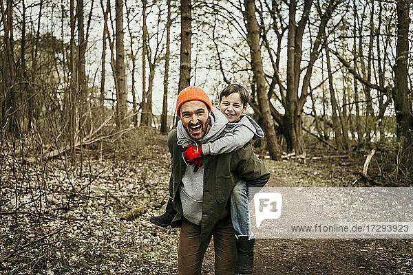 Lachender Vater  der seinen Sohn im Wald huckepack nimmt