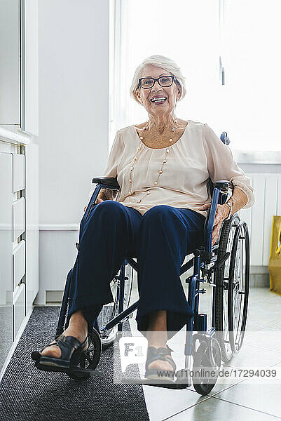 Happy disabled senior woman sitting on wheelchair at home