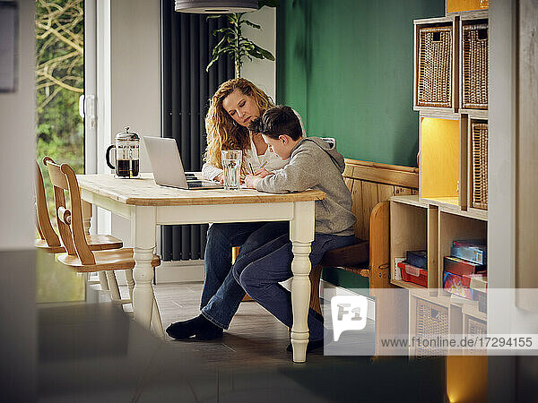 Mutter unterrichtet Sohn zu Hause vor dem Laptop zu Hause