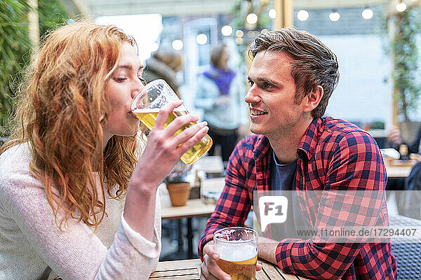 Mann sieht Freundin beim Biertrinken in der Kneipe an