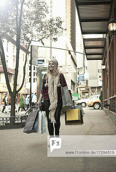 Young woman with shopping bags walking in city