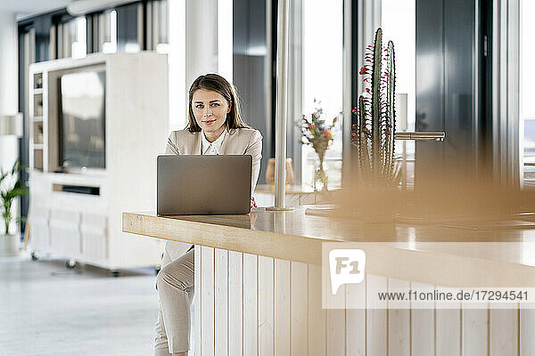 Mittlere erwachsene Geschäftsfrau mit Laptop am Tresen in einer Büro-Cafeteria