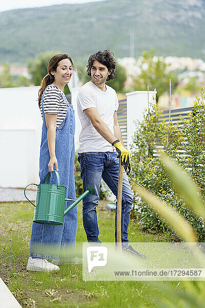 Lächelndes mittleres erwachsenes Paar im Garten stehend