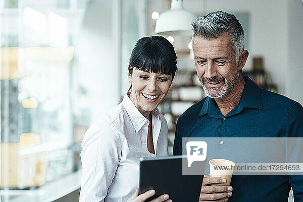 Weibliche und männliche Besitzer nutzen ein digitales Tablet in einem Coffee Shop