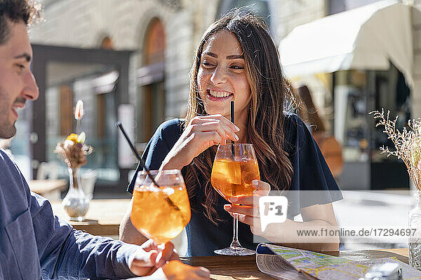 Lächelnde Frau mit Getränk  die einen Mann an einem sonnigen Tag ansieht
