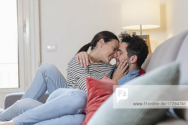 Smiling affectionate couple sitting on sofa at home