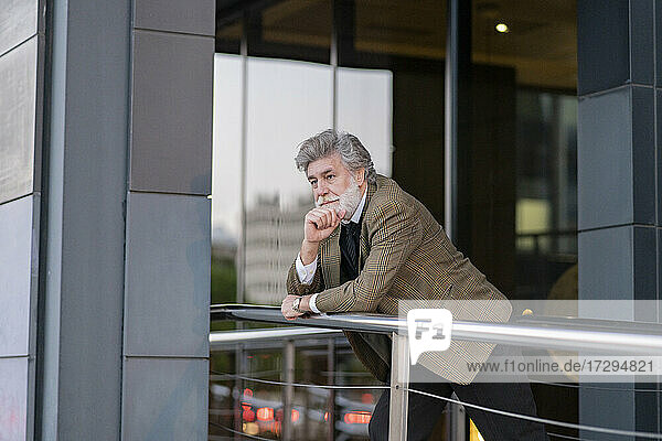 Thoughtful male professional leaning on railing