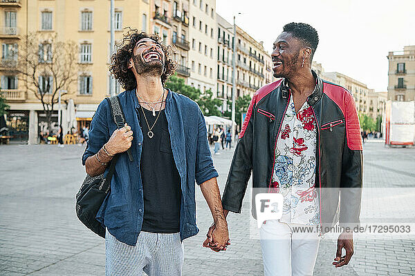 Happy gay couple with holding hands walking on road