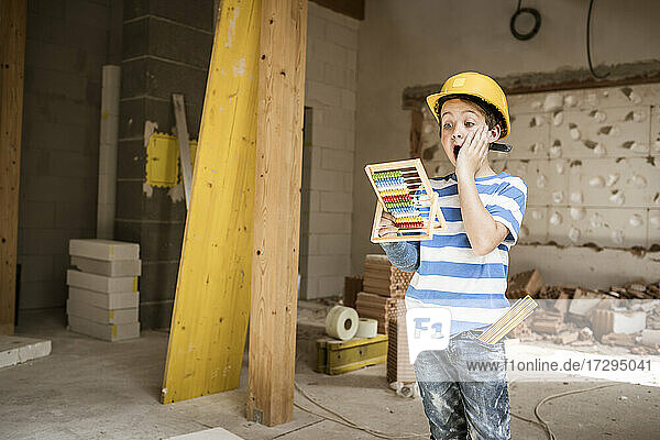 Überraschender Junge mit Abakus beim Wiederaufbau eines Hauses