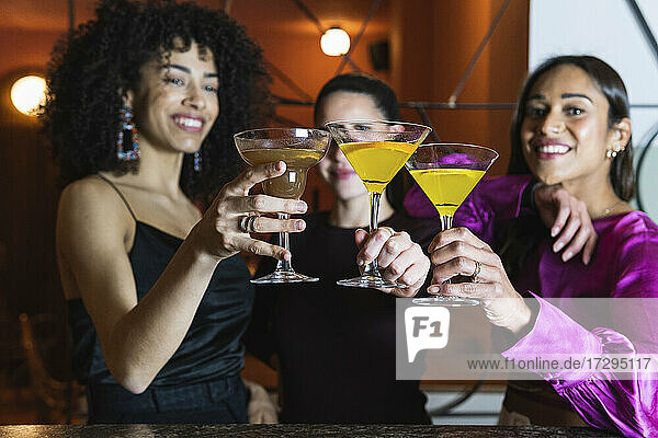 Weibliche Freunde stoßen in einem Restaurant mit einem Martini-Glas an