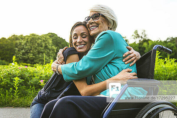 Glückliche Enkelin und Großmutter umarmen sich im Park