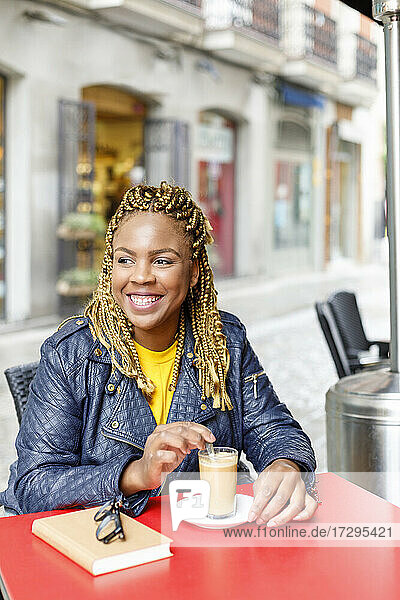 Lächelnde Frau  die wegschaut  während sie im Café sitzt