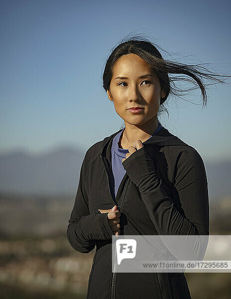 Porträt einer nachdenklichen Frau in Sportkleidung in einer Landschaft stehend