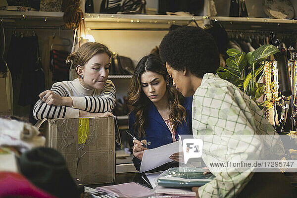 Multi-ethnic female colleagues discussing over document at boutique