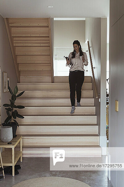 Geschäftsfrau geht die Treppe hinunter  während sie im Büro zu Hause arbeitet