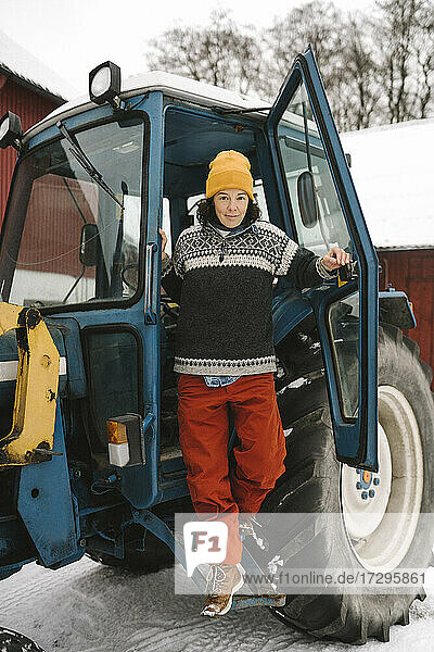 Reife Frau in voller Länge beim Aussteigen aus einem Traktor im Winter