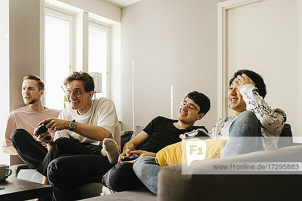 Junge männliche Freunde spielen Videospiel im Wohnzimmer