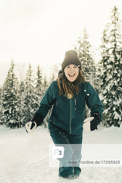 Portrait of happy woman walking on snow at tourist resort