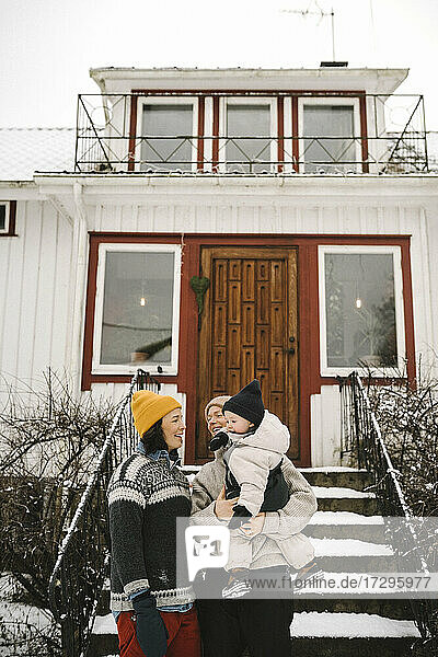 Lesbisches Paar mit Tochter vor dem Haus stehend im Winter