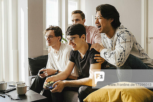 Smiling multi-ethnic male friends playing video game in living room