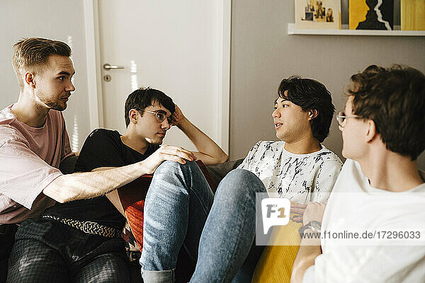 Multi-ethnic male friends comforting young man while sitting in living room