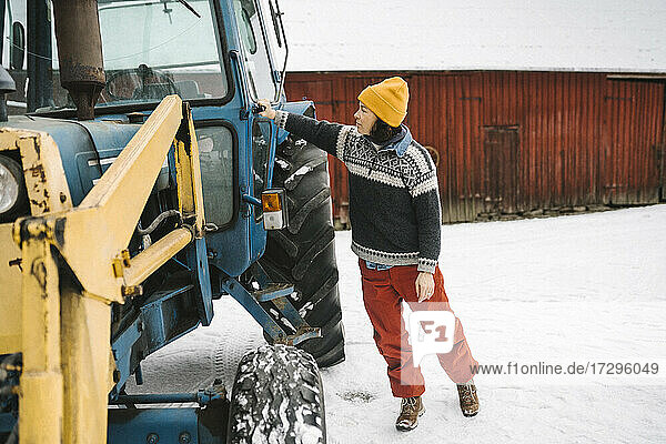 Reife Frau in voller Länge  die die Tür des Traktors im Winter schließt