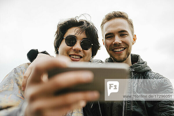 Happy multi-ethnic male friends taking selfie on mobile phone
