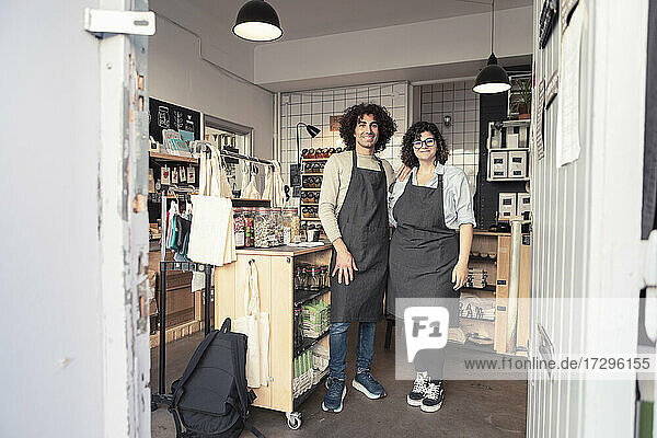 Full length of smiling male and female entrepreneurs standing in organic store