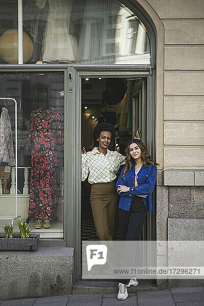 Female colleagues standing at doorway in clothing store