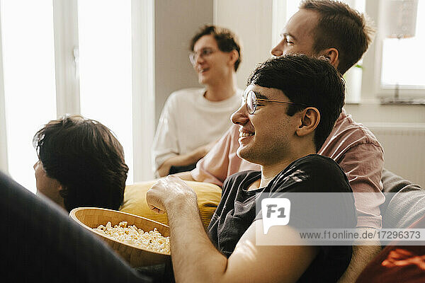 Multi-ethnic male friends having popcorn while watching sports in living room
