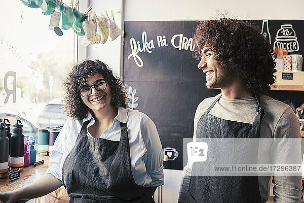 Cheerful male and female co-owners with curly hair working at organic shop