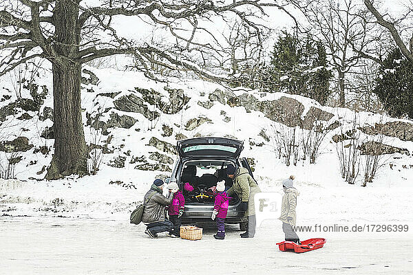 Familie im Urlaub beim Entladen des Kofferraums im Winter