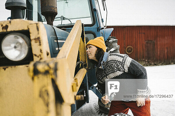 Reife Frau  die einen Traktor im Winter analysiert