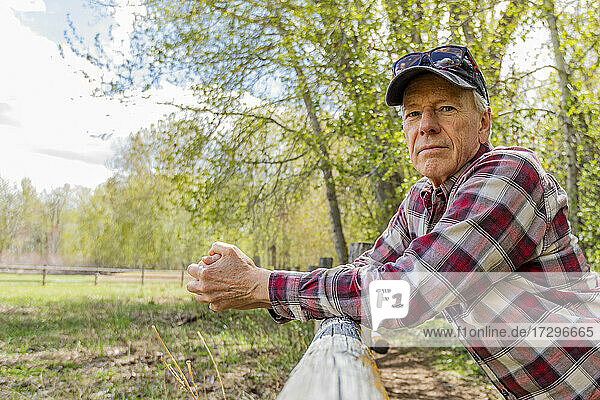 Porträt eines älteren Bauern  der sich an einen Holzzaun in der Nähe von Sun Valley lehnt