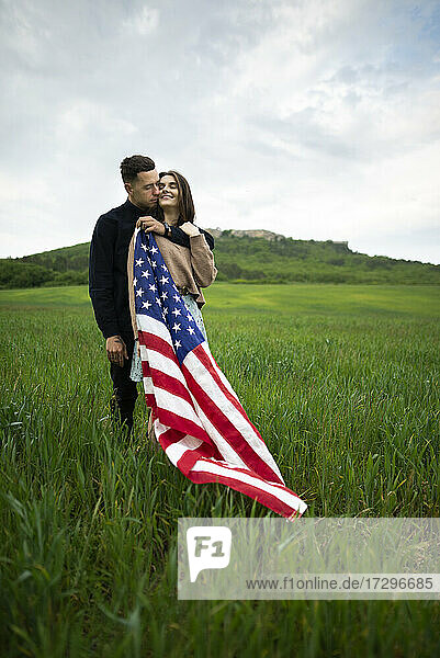 Young couple with American flag in wheat field