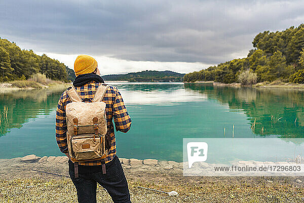 Tourist schaut von seinem Rücken auf den schönen und ruhigen türkisfarbenen See