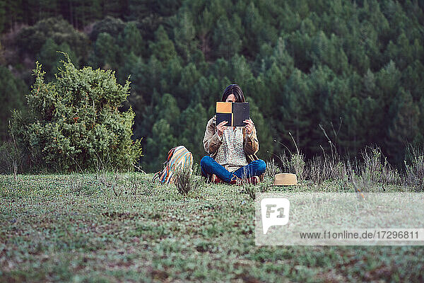 Woman in the mountains reads a book in a meadow.